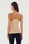 A woman with long hair wearing the SPLITS59 Loren Seamless Waist Length Tank in Nude and black leggings, facing away from the camera against a light background.