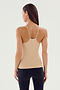 A woman with long hair wearing the SPLITS59 Loren Seamless Waist Length Tank in Nude and black leggings, facing away from the camera against a light background.