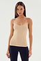 A person with long hair wearing the SPLITS59 Loren Seamless Waist Length Tank in Nude and black pants stands against a plain background.