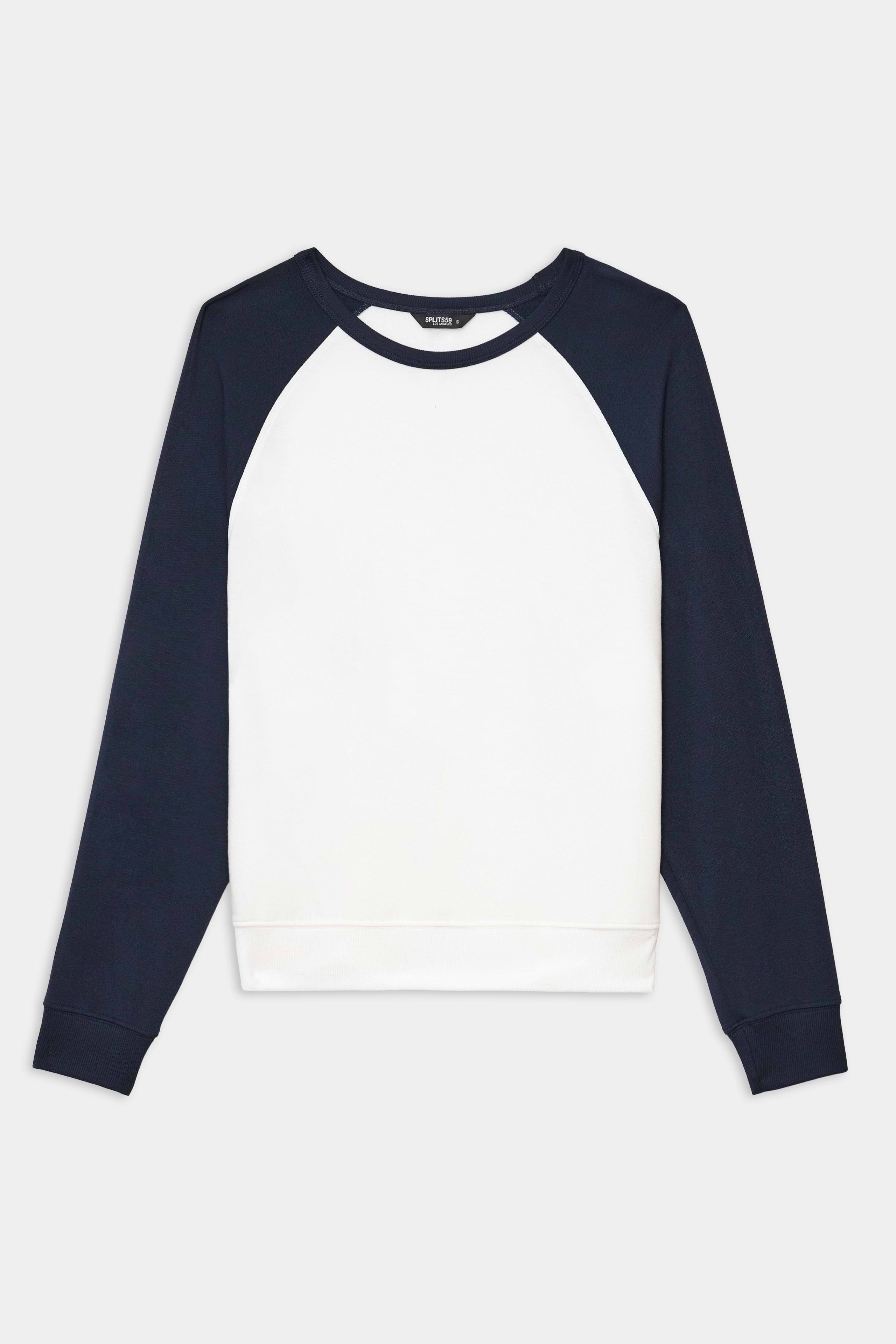 The SPLITS59 Andie Oversized Colorblock Fleece in Indigo/White features white front and back panels with dark navy raglan sleeves and collar, crafted from a soft modal spandex blend, shown laid flat on a white background.