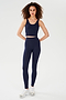 A person stands against a plain background wearing the SPLITS59 Sprint Rigor Bralette in Indigo with matching high-waisted leggings and white sneakers.