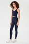 A person wears the SPLITS59 Sprint Rigor Bralette in Indigo with matching high-waisted leggings and white sneakers, standing against a plain white background, showcasing a multi-sport performance look.