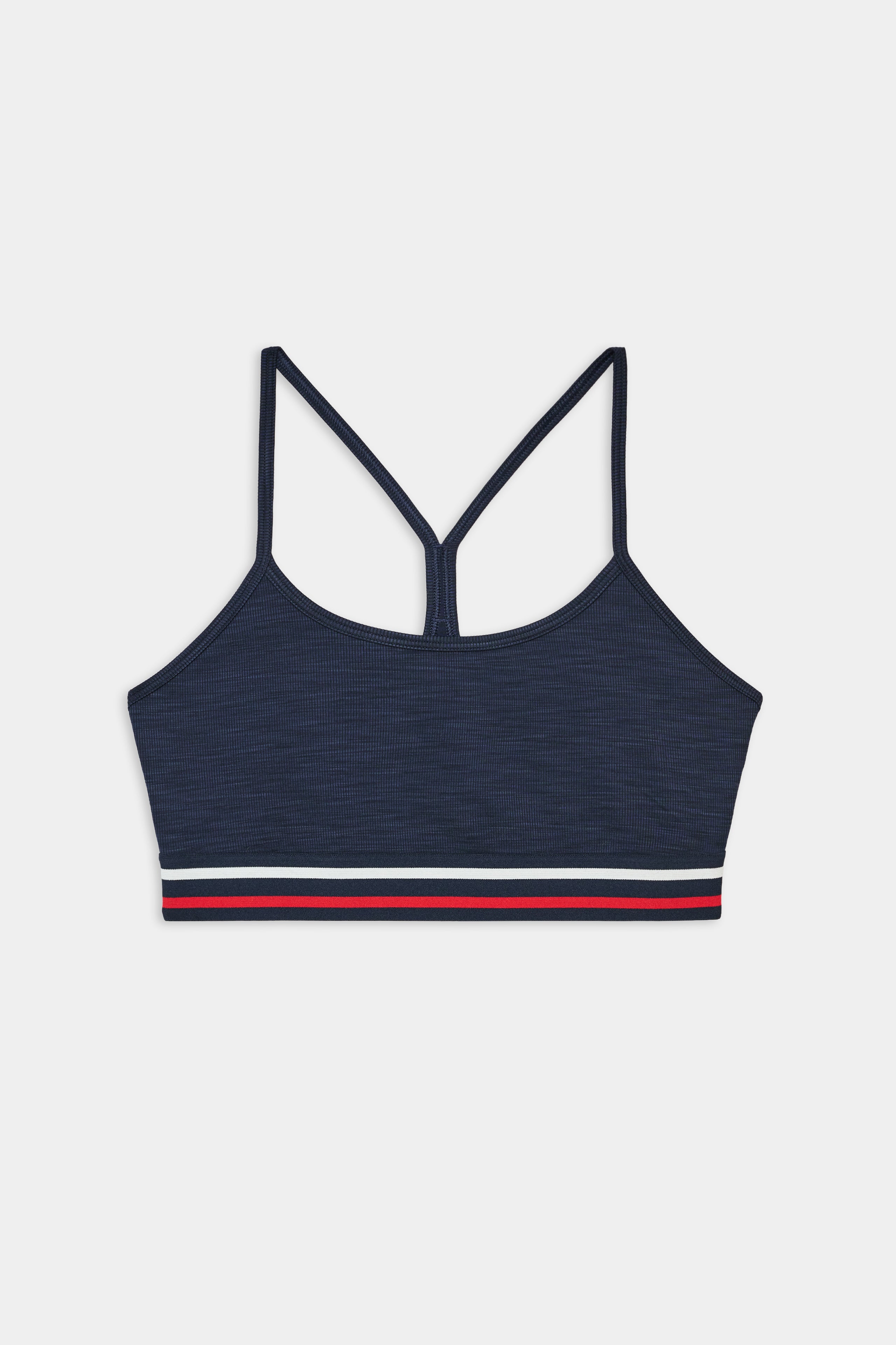 SPLITS59 Cali Active Rib Bra in Heather Indigo features thin crisscross straps and a red, white, and navy striped band, shown on a plain white background.