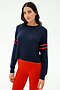 A woman wears the SPLITS59 Brooks Stripe Fleece Sweatshirt in Indigo/Lotus Red, paired with bright red leggings, standing against a plain white background.