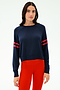 A woman faces forward wearing the SPLITS59 Brooks Stripe Fleece Sweatshirt in Indigo/Lotus Red and bright red leggings against a plain light background.