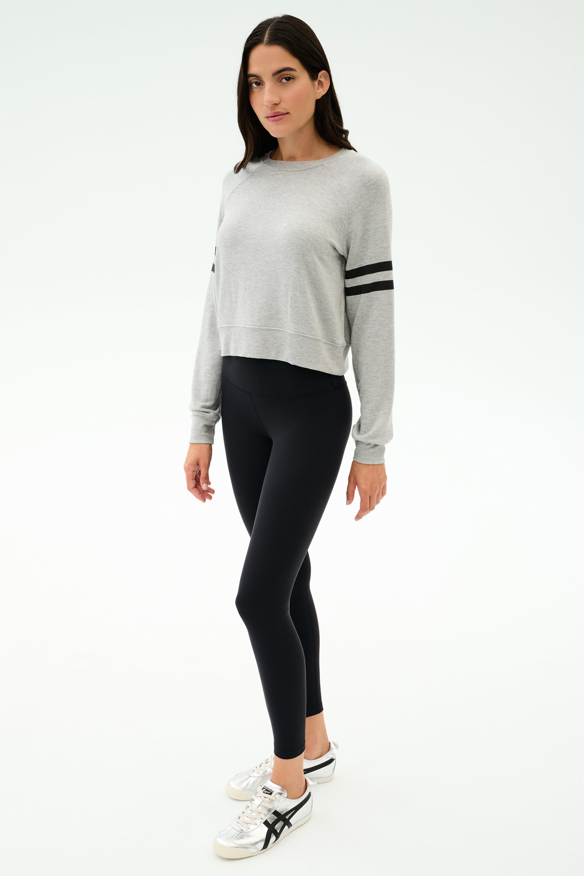 A woman in the SPLITS59 Brooks Stripe Fleece Sweatshirt in Heather Grey/Black and black leggings, crafted from drape-stretch modal fabric and made in Los Angeles.