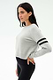 A woman in profile wears the SPLITS59 Brooks Stripe Fleece Sweatshirt in Heather Grey/Black with two black sleeve stripes and black leggings, crafted from drape-stretch modal, standing against a plain background.