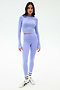 A woman wears the SPLITS59 Louise Rib Long Sleeve Crop in Purple Haze with matching high-waisted leggings, white socks, and silver sneakers against a plain white background.