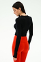 A woman stands facing away against a plain light background, wearing the SPLITS59 Louise Rib Long Sleeve Crop in black with high-waisted red leggings.