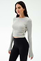 A woman stands against a plain background wearing the SPLITS59 Louise Rib Long Sleeve Crop in Heather Grey and high-waisted black leggings.