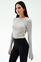 A woman stands against a plain background wearing the SPLITS59 Louise Rib Long Sleeve Crop in Heather Grey and high-waisted black leggings.