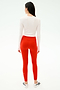 A woman faces away, wearing SPLITS59 Sprint High Waist Rigor 7/8 leggings in Lotus Red and a white long-sleeve top, paired with white sneakers with black accents, all set against a plain white background.