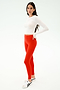 A person wears the SPLITS59 Louise Rib Long Sleeve Crop in white, paired with bright red leggings and white sneakers, standing against a plain white background.