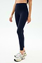 A person wearing SPLITS59 Sprint High Waist Rigor 7/8 leggings in Indigo and white athletic shoes stands against a plain light background.