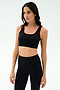 A woman wears the SPLITS59 Sprint Rigor Bra in black, paired with high-waisted leggings, standing against a light background—ready for gym workouts or multisport performance.