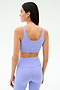 A woman faces away, wearing the SPLITS59 Sprint Rigor Bra in Purple Haze with matching high-waisted leggings—ideal for gym workouts and multi-sport performance—set against a plain light background.