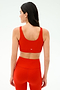 A woman is shown from the back wearing the SPLITS59 Sprint Rigor Bra in Lotus Red with matching high-waisted leggings, perfect for multi-sport performance, set against a plain light background.
