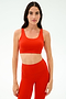 A woman wears a SPLITS59 Sprint Rigor Bra in Lotus Red, standing forward against a plain white background—ideal for multi-sport performance and intense gym workouts.