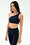 A woman in the SPLITS59 Josie Airweight One Shoulder Bra in Indigo/White and matching high-waisted leggings with white trim stands against a plain light background, ready for hot yoga or Pilates.