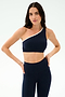A woman wears the SPLITS59 Josie Airweight One Shoulder Bra in Indigo/White with matching high-waisted leggings, hands on hips—ideal for Pilates or hot yoga—set against a plain background.