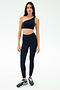 A woman faces forward wearing the SPLITS59 Josie Airweight One Shoulder Bra in Indigo/White with matching high-waisted leggings and dark sneakers, standing against a plain white background.