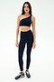A woman faces forward wearing the SPLITS59 Josie Airweight One Shoulder Bra in Indigo/White with matching high-waisted leggings and dark sneakers, standing against a plain white background.