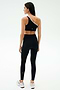 A woman stands facing away on a light background, wearing the SPLITS59 Josie Airweight One Shoulder Bra in black/white with matching black leggings featuring white side stripes, paired with white athletic shoes.
