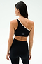 A woman faces away, wearing the SPLITS59 Josie Airweight One Shoulder Bra in Black/White with matching high-waisted leggings, set against a plain light background.