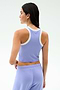 A woman is shown from the back wearing the SPLITS59 Kiki Rib Crop Tank in Purple Haze/White with matching purple pants, ideal for gym workouts, set against a plain light background.