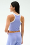 A woman is shown from the back wearing the SPLITS59 Kiki Rib Crop Tank in Purple Haze/White with matching purple pants, ideal for gym workouts, set against a plain light background.