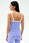 A woman with long dark hair is seen from the back wearing the SPLITS59 Monah Rigor Tank in Purple Haze/White, paired with matching leggings made from soft Rigor fabric, against a plain light background.