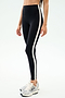 A person wearing SPLITS59 Clare High Waist Rigor 7/8 leggings in Black/White stands against a plain, light background, paired with silver athletic shoes.