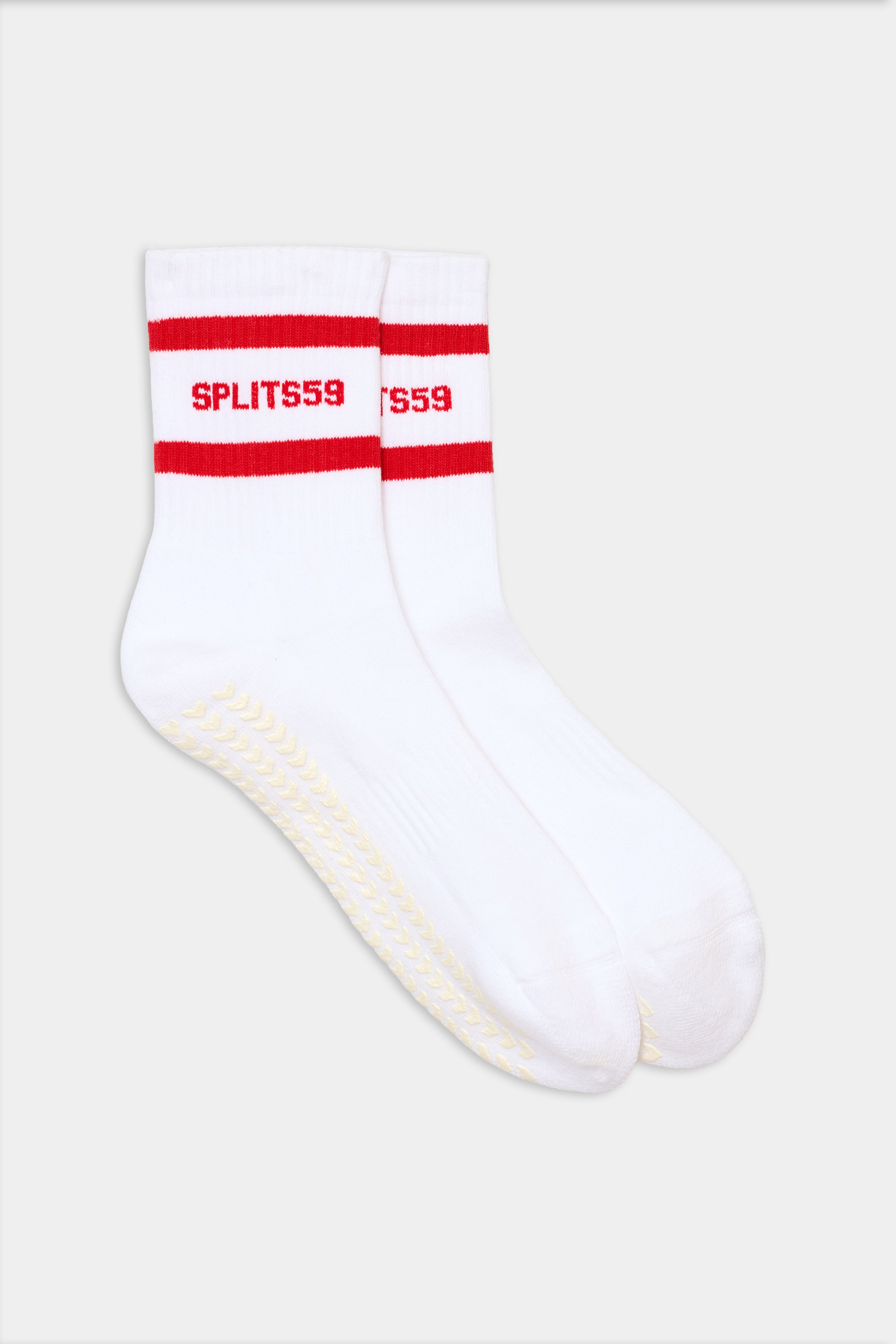 The SPLITS59 Logo Stripe Ankle Socks With Grip are white ankle socks with two red stripes and "SPLITS59" in red near the cuff, plus a textured grip pattern on the soles.