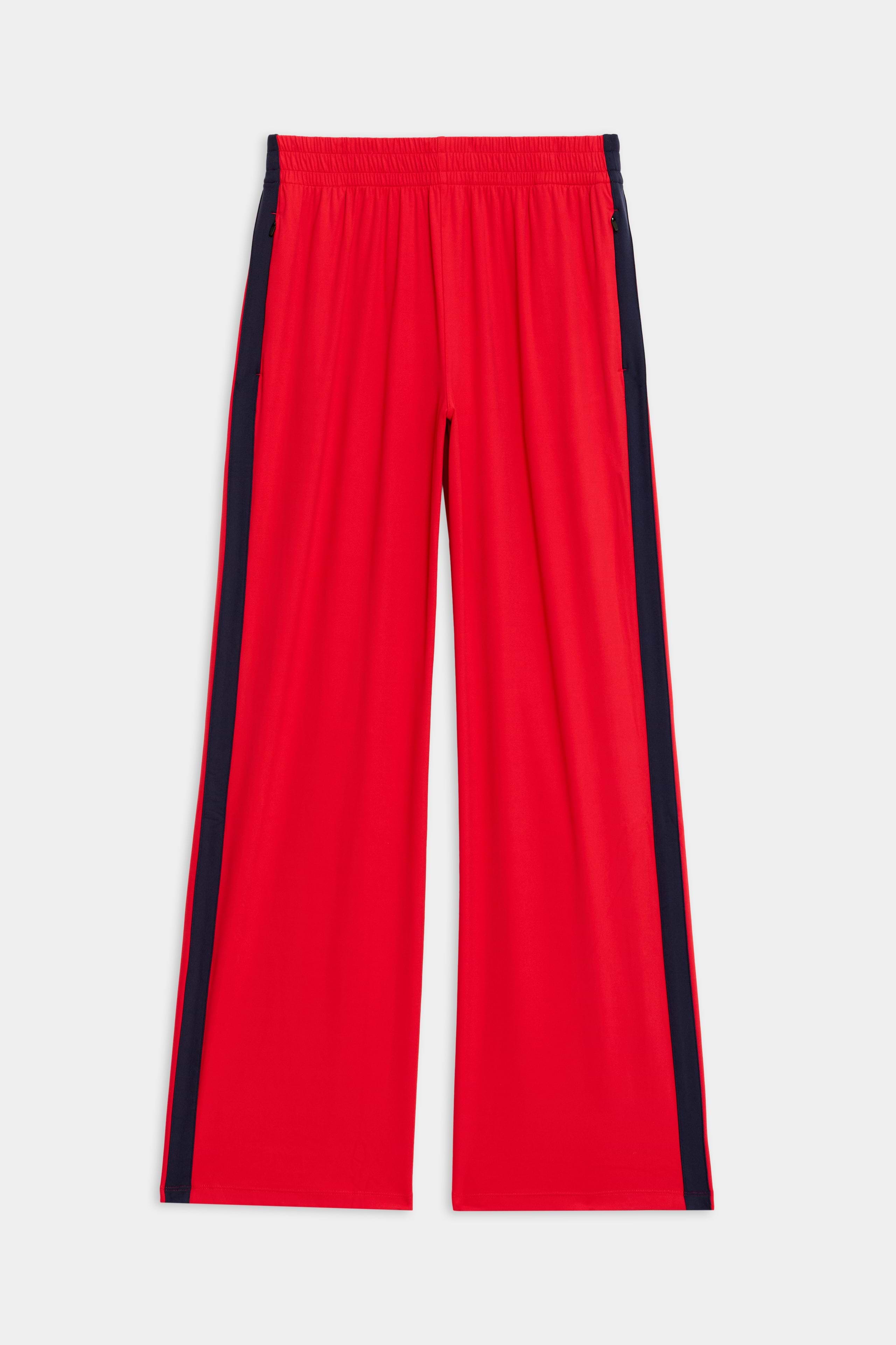 The Maxie Rigor Track Pant by SPLITS59 in Pirate Red/Indigo has a wide-leg design with an elastic waistband, sleek black side stripes, and is crafted from premium Rigor fabric, showcased flat on a white background.