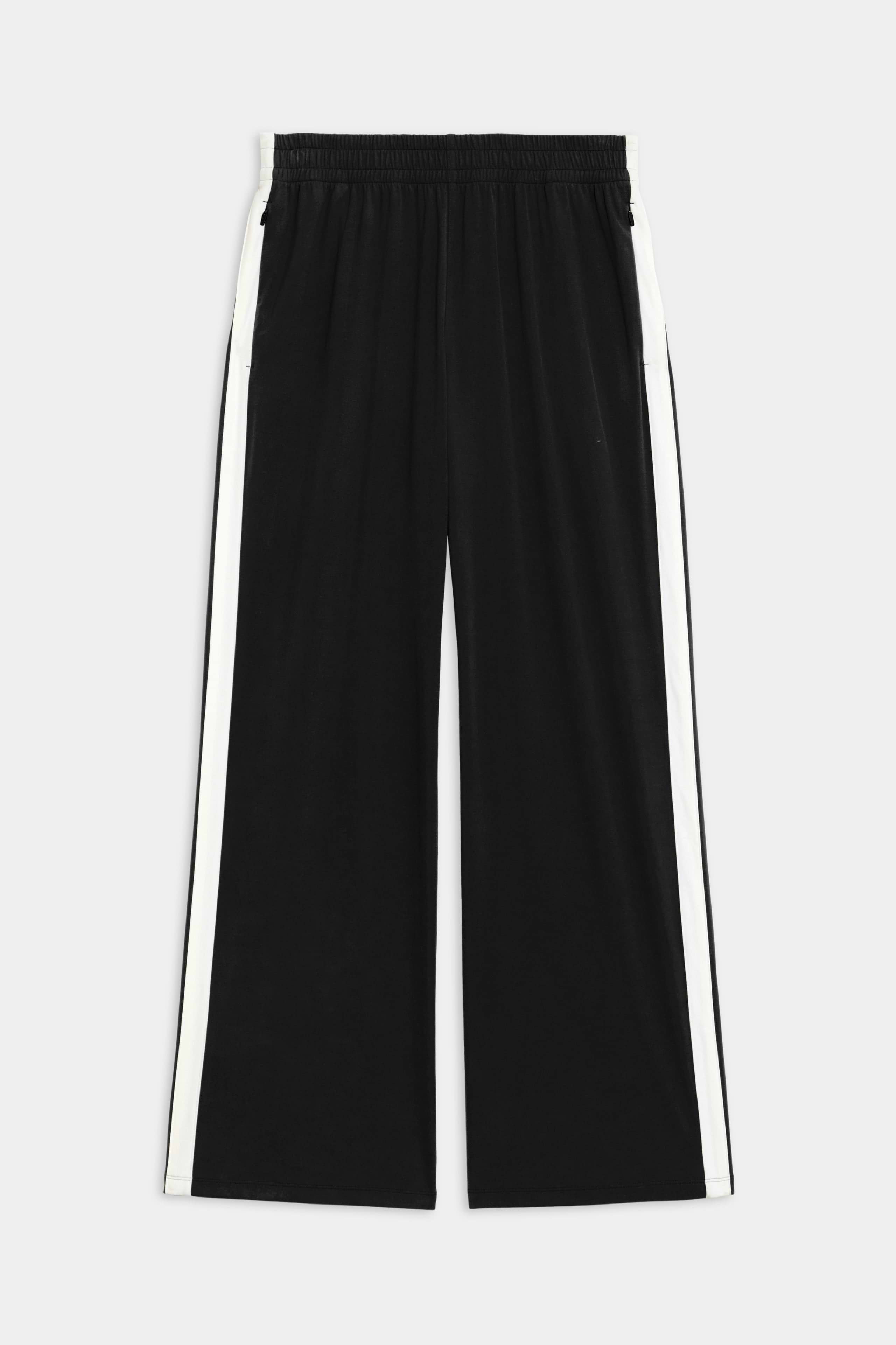 The SPLITS59 Maxie Rigor Track Pant - Black/White showcases a wide-leg silhouette, white side stripes, elastic waistband, and two side pockets, made from durable Rigor fabric and displayed on a plain background.