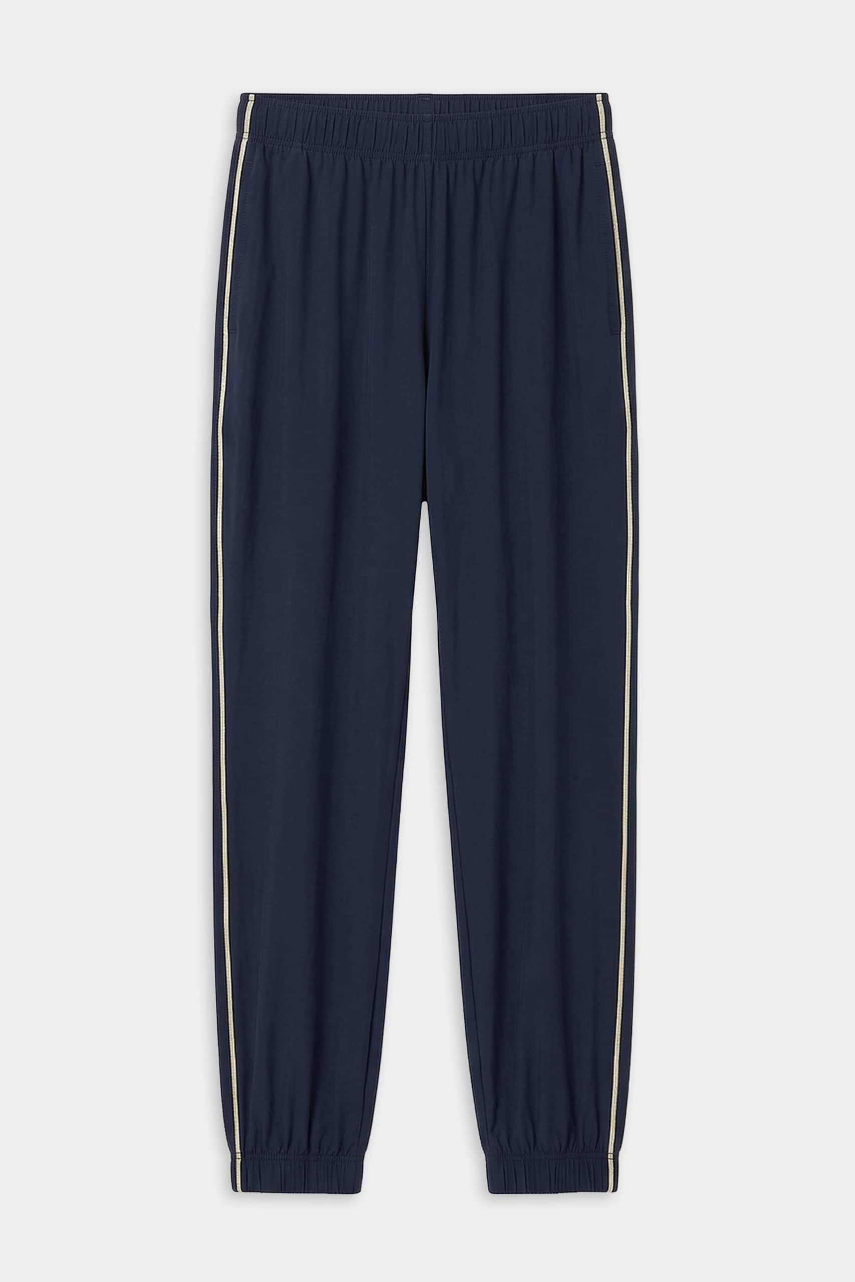 The SPLITS59 Megan Woven Nylon Jogger w/ Piping in Indigo/Creme features an elastic waistband and cuffs, white side piping, and is crafted from stretchy fabric for comfort and flexibility.