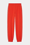 The SPLITS59 Megan Woven Nylon Jogger w/ Piping in Lotus Red/Creme features white side piping, an elastic waistband, and elastic cuffs. Crafted from a spandex-nylon blend and shown laid flat on a white background.