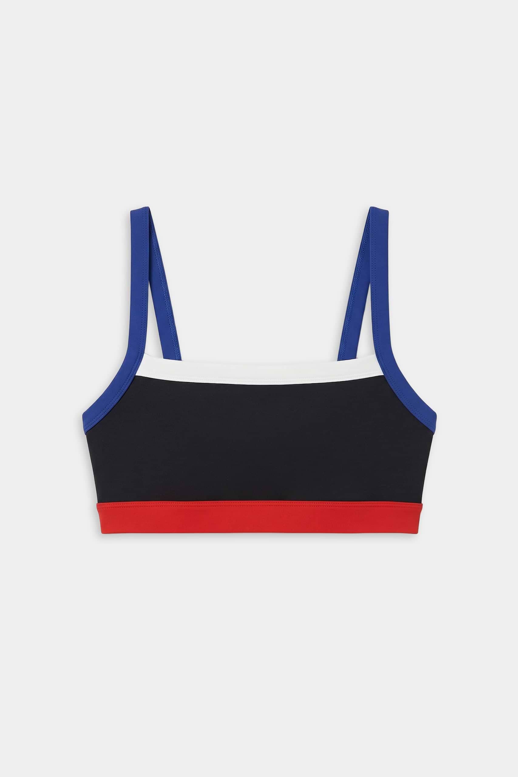 The SPLITS59 Monah Rigor Bra - Black/Cobalt features a color-blocked design with blue straps, a white upper band, black body, and red lower band—ideal for workouts. Shown on a white background.