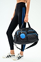 Wearing black leggings with blue stripes and white sneakers, a person carries the SPLITS59 MZW x Splits59 Duffle—a quilted black bag with blue accents and a round blue and red keychain.