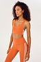 Side view of girl wearing orange sports bra with two thin white stripes down the side and orange leggings