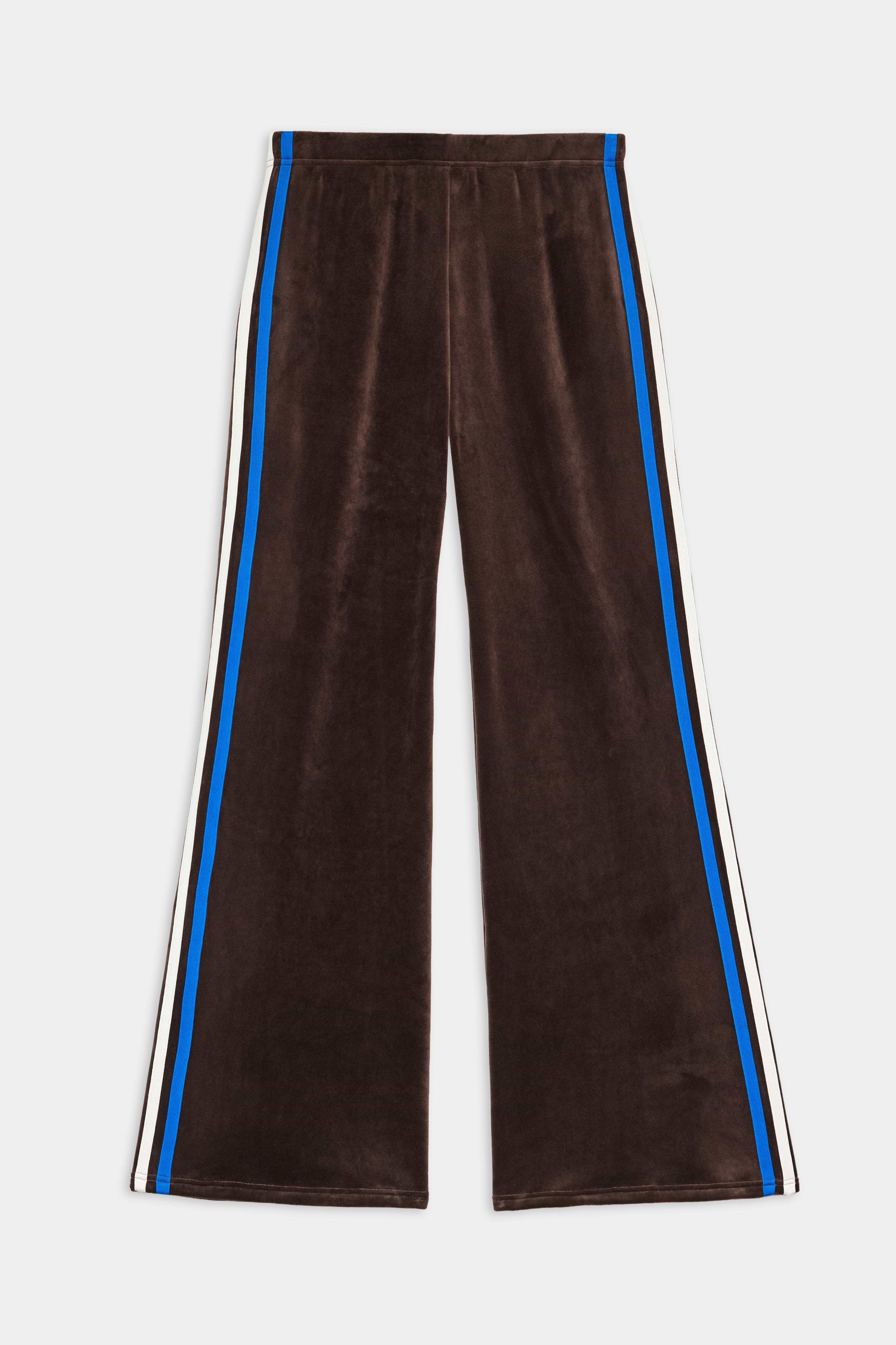 The SPLITS59 Heritage Velour Pant in Dark Chocolate/Classic Blue features blue and white side stripes, ankle length, a wide-leg silhouette, and is shown laid flat on a white background.