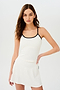 Front view of girl wearing white spaghetti strap tank top with dark blue spaghetti straps and a white skirt