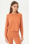 Front view of woman with brown hair wearing orange cropped sweatshirt and orange leggings