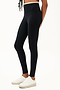 Side view of girl wearing black leggings with thin white band around waist with white shoes
