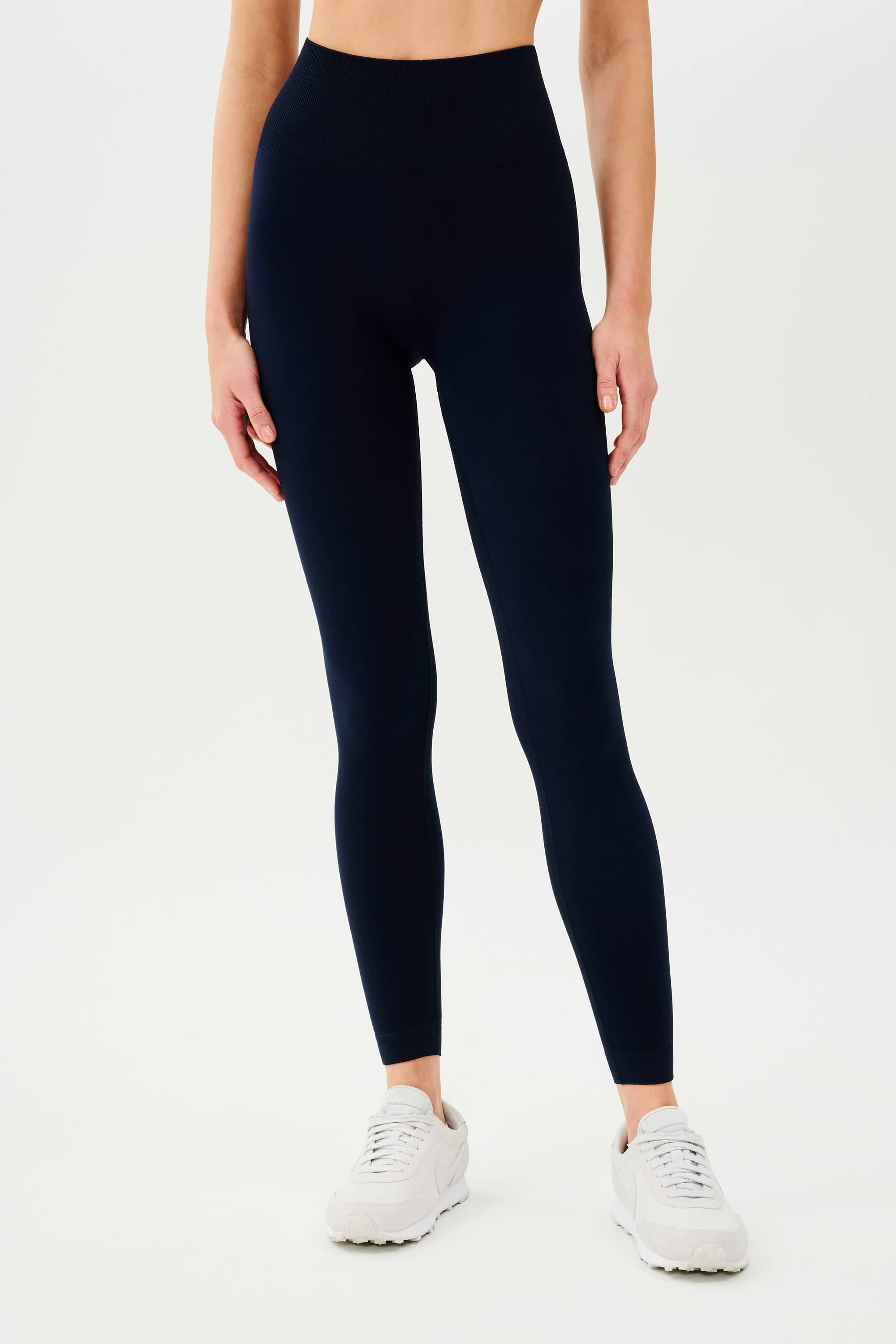 The back view of a woman wearing SPLITS59 Loren Seamless High Waist Full Length leggings in Indigo.
