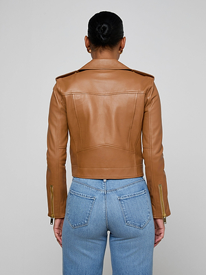 A person with dark hair in a neat bun wears the tan Blakely Leather Biker Jacket and light blue jeans, facing away from the camera against a plain light gray background.