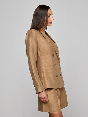 A woman stands in profile against a plain background, wearing the tan Colin Linen-Blend Blazer and matching shorts. Her long brown hair is worn down and straight.