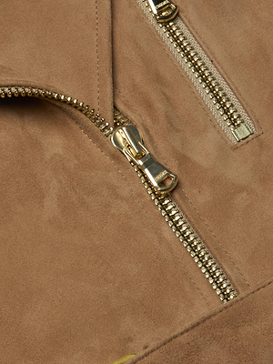 Close-up of the Dinah Suede Biker Jacket in tan, featuring two gold zips—one horizontal, one diagonal—with detailed stitching and a rich suede texture.