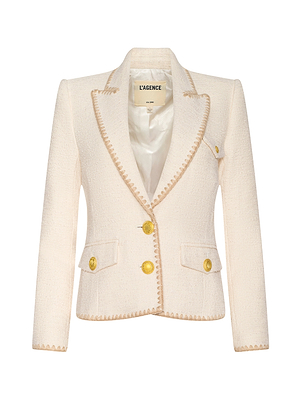 The Wylla Tweed Blazer by L’AGENCE is a cream ecru women’s blazer featuring gold buttons, beige embroidered trim, two front pockets, and a notched lapel.