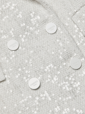 Close-up of the Cambrie Oversized Sequin Blazer, featuring textured cream fabric with white sequins and four white “L’AGENCE PARIS” embossed buttons. A pocket flap appears in the upper right corner.